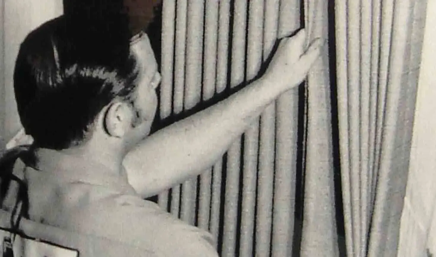 black and white photo of technician adjusting drapes